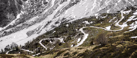 A road winding up towards snowy Alpine peaks in spring